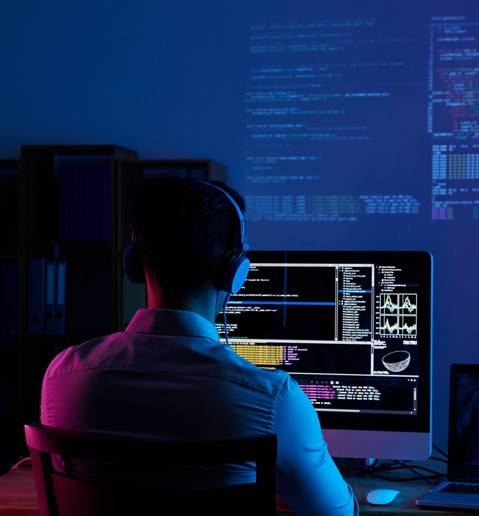 Developer working on code late at night, view from the back